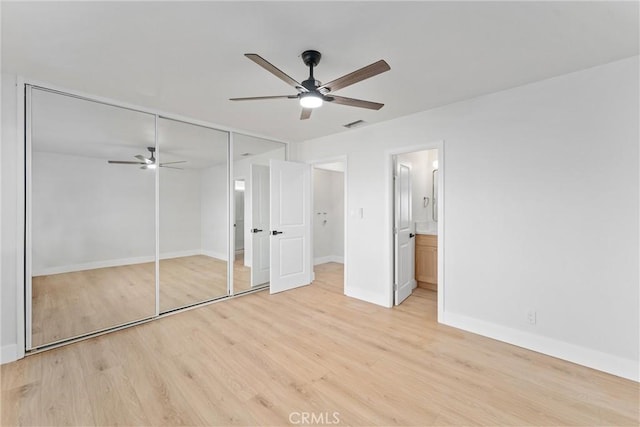 unfurnished bedroom with ensuite bathroom, ceiling fan, baseboards, a closet, and light wood finished floors