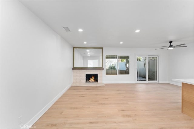 unfurnished living room featuring visible vents, a fireplace, light wood-style flooring, and baseboards