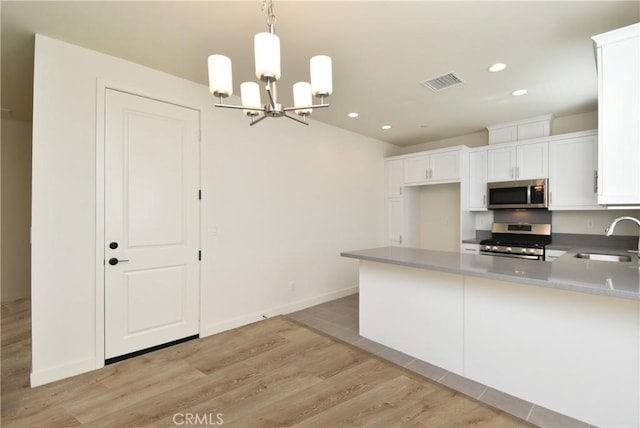 kitchen featuring stainless steel appliances, white cabinets, visible vents, and a sink