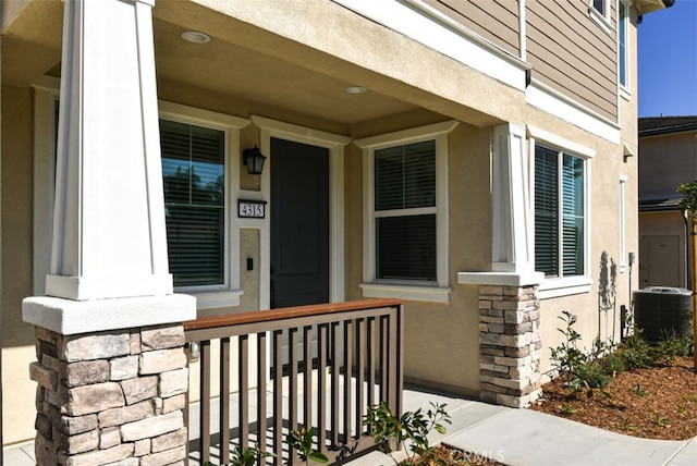 property entrance featuring covered porch, cooling unit, and stucco siding