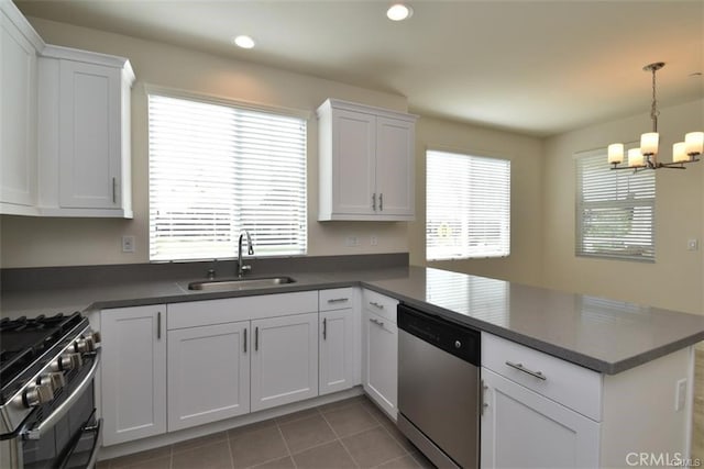 kitchen featuring stainless steel appliances, white cabinetry, a sink, and a peninsula