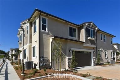 view of front of property featuring a garage, a residential view, and central air condition unit