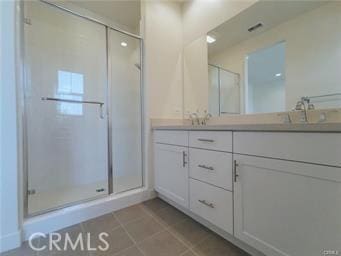 full bathroom featuring double vanity, a shower stall, a sink, and tile patterned floors