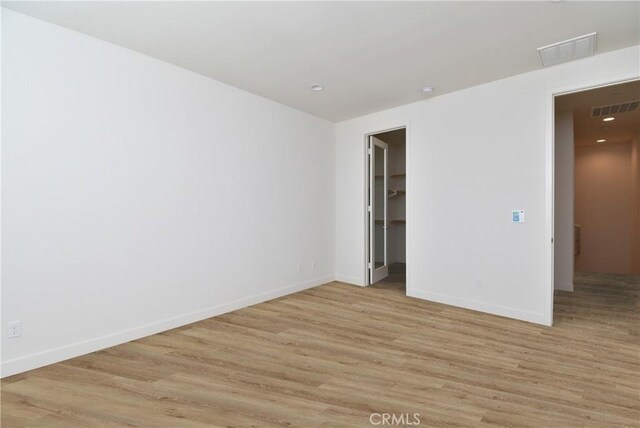 unfurnished room featuring light wood-type flooring, baseboards, and visible vents