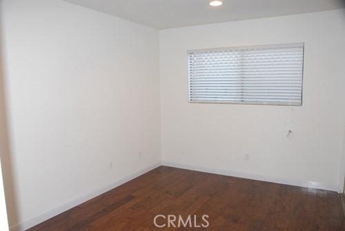 spare room featuring recessed lighting, baseboards, and wood finished floors