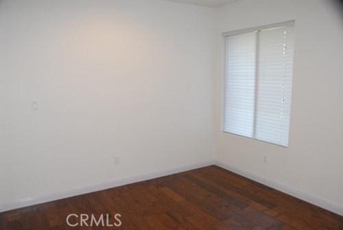 empty room featuring baseboards and dark wood-style flooring