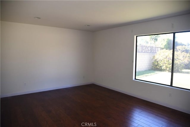 spare room featuring dark wood-style floors and baseboards