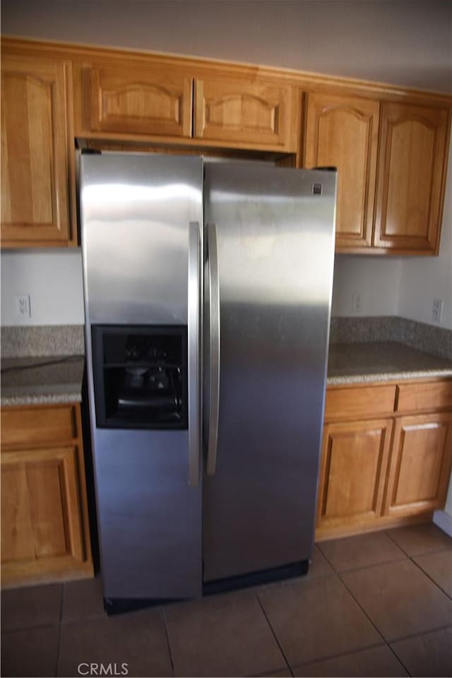 kitchen featuring brown cabinets, dark tile patterned flooring, and stainless steel fridge with ice dispenser