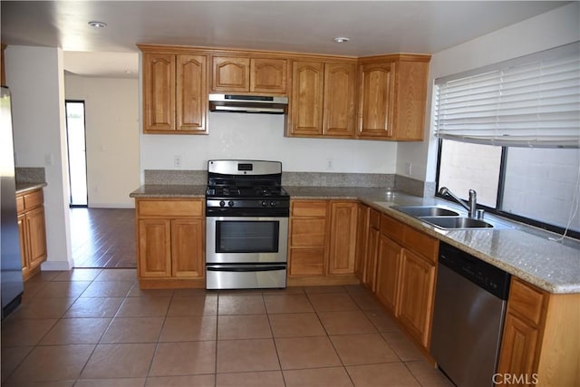 kitchen featuring under cabinet range hood, stainless steel appliances, tile patterned flooring, and a sink