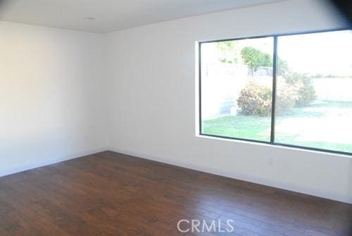 empty room featuring a healthy amount of sunlight and dark wood-style flooring