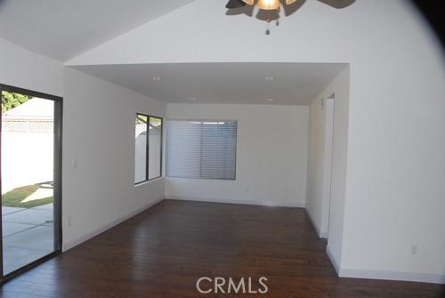 unfurnished room with a ceiling fan, vaulted ceiling, wood finished floors, and baseboards