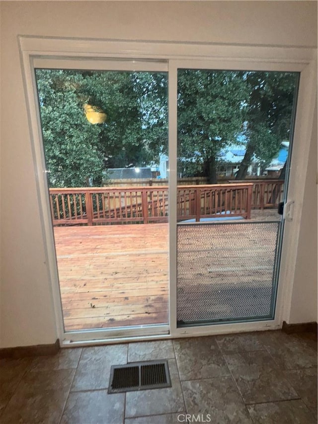 doorway with stone finish flooring, visible vents, and baseboards