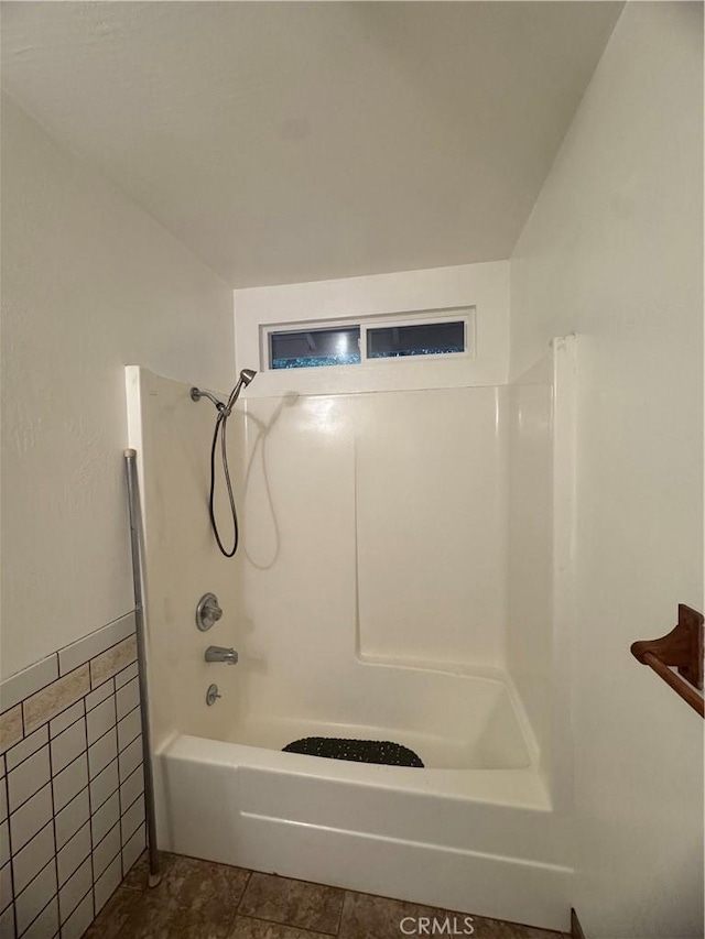 bathroom with shower / washtub combination, tile patterned flooring, and tile walls