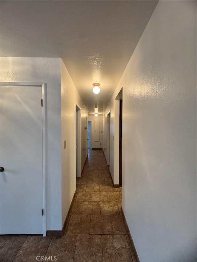 corridor with stone finish floor and baseboards