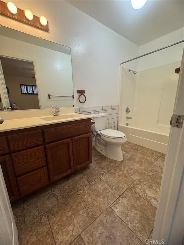 bathroom featuring a wainscoted wall, shower / bathing tub combination, vanity, and toilet