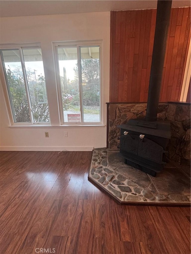 living room with wood finished floors, a wood stove, and baseboards