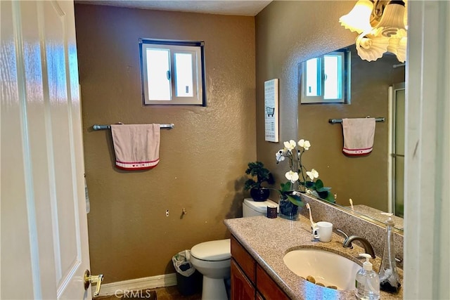 bathroom with baseboards, a textured wall, vanity, and toilet