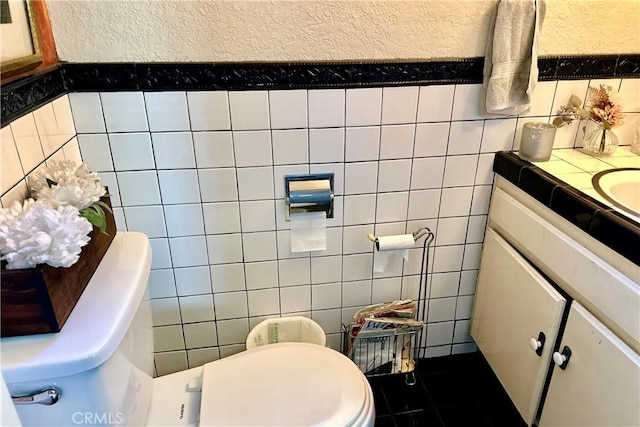 half bathroom featuring tile walls, vanity, and toilet