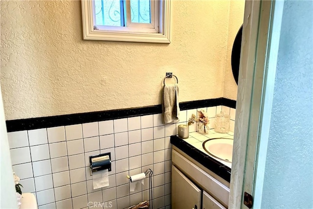 bathroom featuring a textured wall, vanity, and tile walls