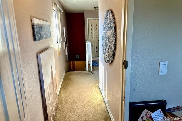 corridor with light carpet and a textured wall