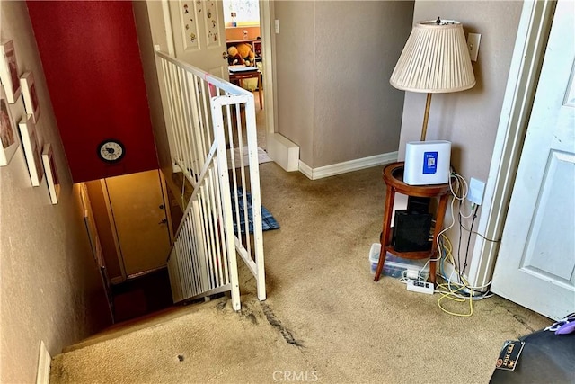 staircase featuring carpet, a textured wall, and baseboards