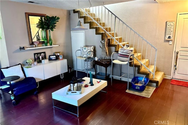 living room featuring a textured ceiling, stairs, visible vents, and wood finished floors