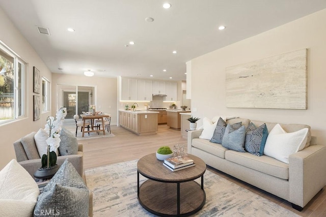 living area featuring light wood finished floors, visible vents, and recessed lighting