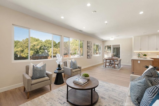 living room with recessed lighting, light wood-style floors, and baseboards