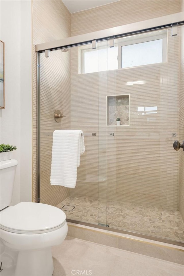 bathroom featuring tile patterned floors, toilet, and a shower stall