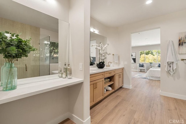 full bathroom with vanity, a shower stall, wood finished floors, and baseboards