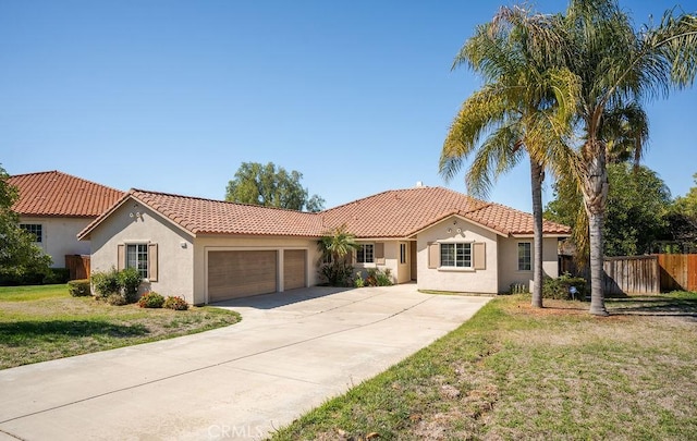 mediterranean / spanish house with stucco siding, a front lawn, a tile roof, fence, and a garage