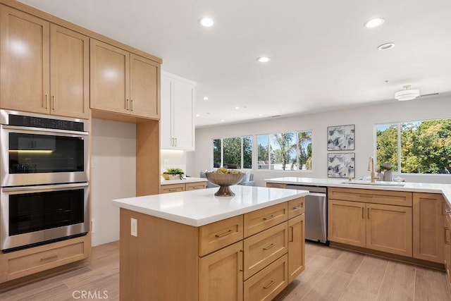 kitchen with a sink, light countertops, light wood-type flooring, and stainless steel appliances