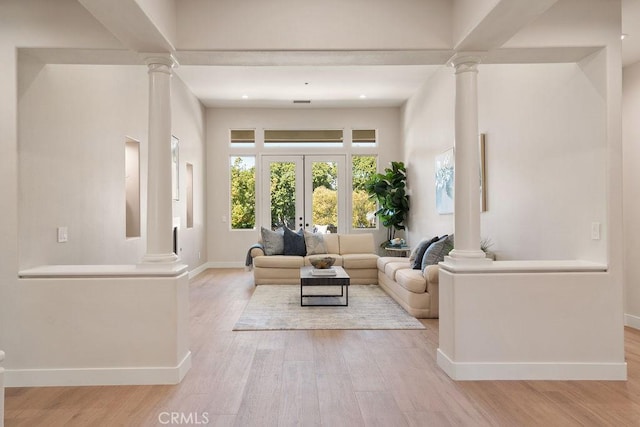 living area with french doors, wood finished floors, baseboards, and ornate columns