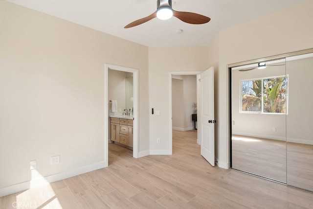 unfurnished bedroom featuring light wood-style flooring, a closet, connected bathroom, baseboards, and ceiling fan