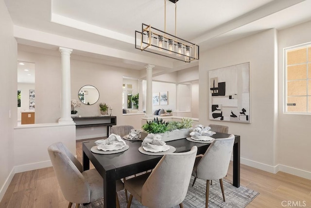 dining room with light wood-type flooring, baseboards, and ornate columns