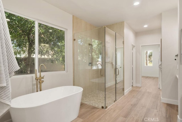 bathroom featuring recessed lighting, a freestanding tub, wood finished floors, and a shower stall