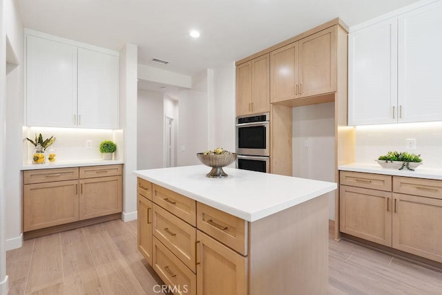 kitchen featuring double oven, light wood-style floors, visible vents, and light countertops