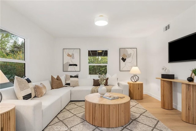 living area featuring visible vents, light wood-style flooring, and baseboards