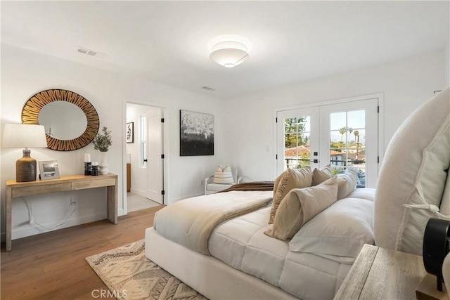 bedroom with wood finished floors, visible vents, baseboards, access to exterior, and french doors