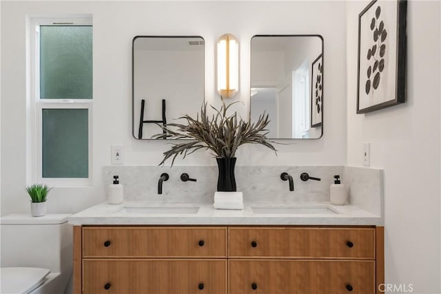 bathroom featuring toilet, tasteful backsplash, double vanity, and a sink