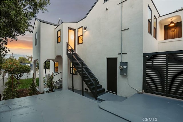 exterior space featuring stairs, a patio, and stucco siding