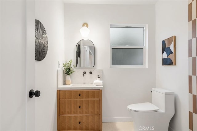 bathroom featuring vanity, backsplash, toilet, and baseboards