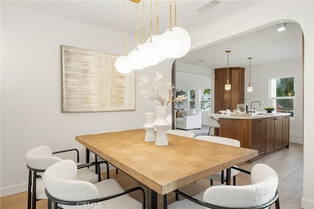 dining room with arched walkways, visible vents, plenty of natural light, and baseboards