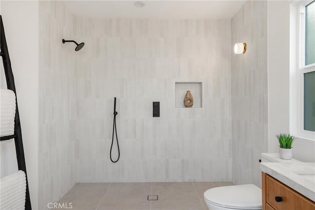 bathroom featuring toilet, tile patterned floors, tiled shower, and vanity