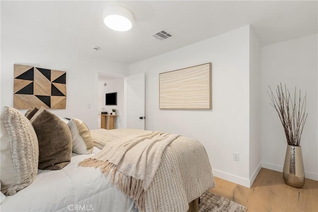 bedroom with baseboards, visible vents, and wood finished floors