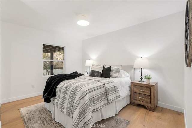 bedroom featuring light wood finished floors and baseboards