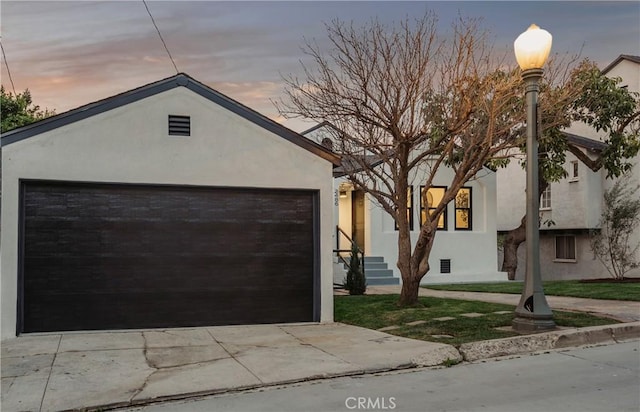 view of front of property featuring driveway, an outdoor structure, and stucco siding