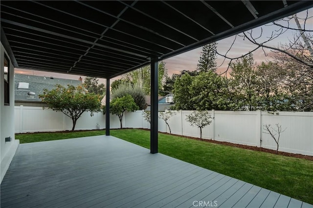 deck at dusk featuring a fenced backyard and a yard