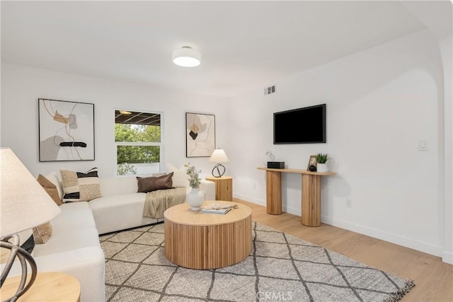 living area featuring light wood finished floors, baseboards, and visible vents