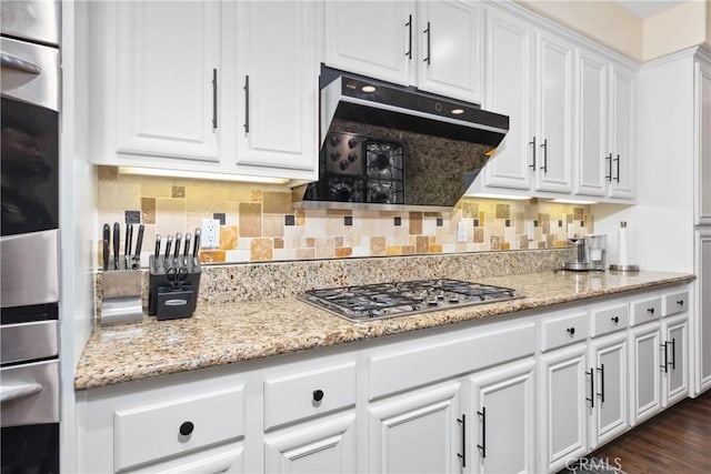 kitchen with stainless steel appliances, white cabinets, decorative backsplash, and exhaust hood